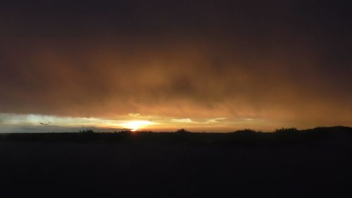 Scenic view of dramatic sky over silhouette landscape