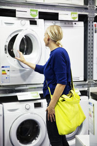 Woman looking at washing machine in shop