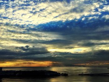 Scenic view of sea against cloudy sky at sunset