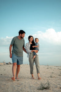 Rear view of couple standing at beach against clear sky