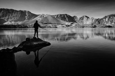 Man standing on lake against mountain range