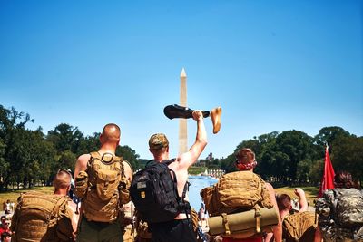 Rear view of tourist holding artificial leg at washington monument against clear blue sky