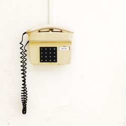 Close-up of telephone booth against white wall