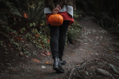 Low section of man standing by pumpkin