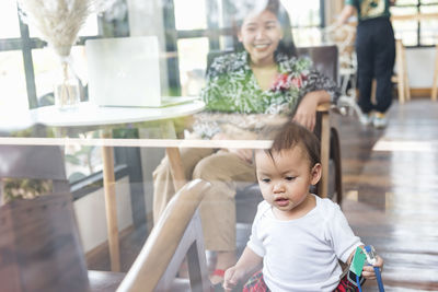 A mother-daughter family with a small daughter in the house, photographed through the glass.