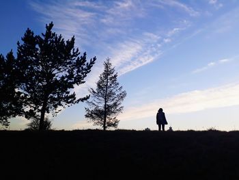 Silhouette man standing on field against sky during sunset