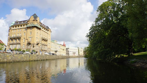 Reflection of building in lake against cloudy sky