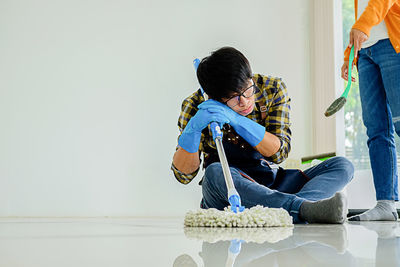 Tired man cleaning tiled floor at home