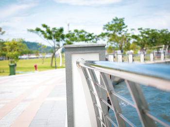 Close-up of railing by swimming pool against sky on sunny day