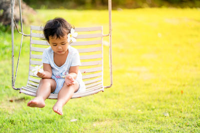 Cute girl sitting on swing in park