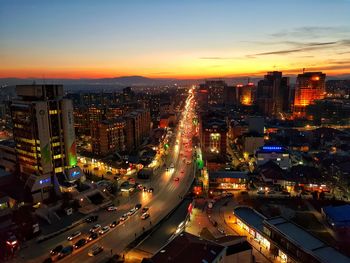 High angle view of illuminated city street and buildings against sky during sunset