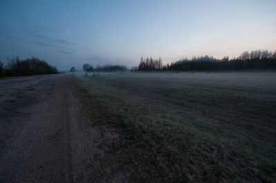 Dirt road on field against sky