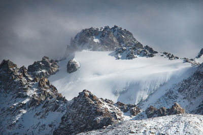 Rocks on the tuyuk-su glacier and snow-capped mountains n sunny weather in winter