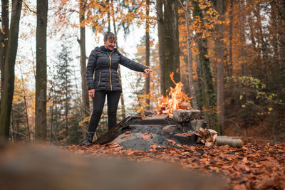 Woman standing by campfire in forest