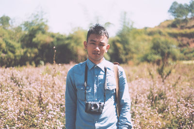 Portrait of man with camera standing on field