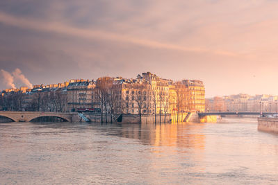 Historic residential buildings located on shore of rippling river flowing in paris in winter evening