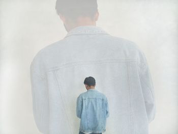 Rear view of man standing against white wall