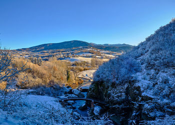 Scenic view of snowcapped mountains against clear blue sky