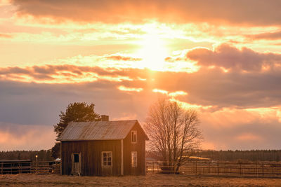 House on field against sky during sunset