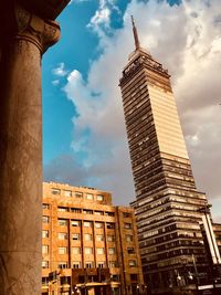 Low angle view of skyscrapers against cloudy sky