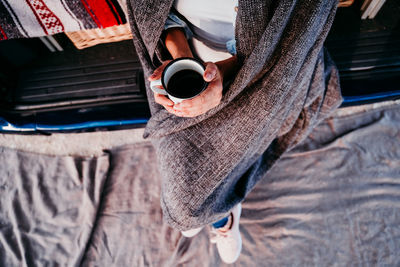 Midsection of woman drinking coffee while sitting in caravan