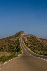 Road leading towards mountain against sky