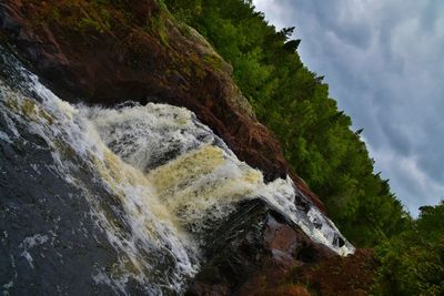 Low angle view of waterfall against sky