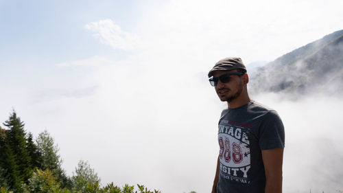 Young man looking at camera against sky