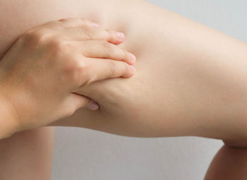 Cropped image of woman pinching thigh