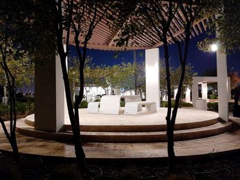 Empty chairs and table in swimming pool at night