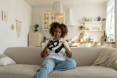 Young woman using mobile phone while sitting on sofa at home