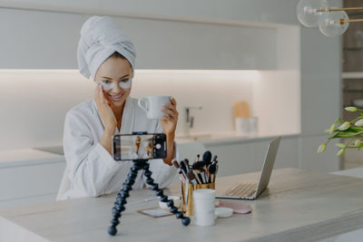 Smiling woman with medical eye patches vlogging at home