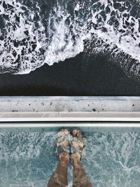 Low section of person standing by swimming pool