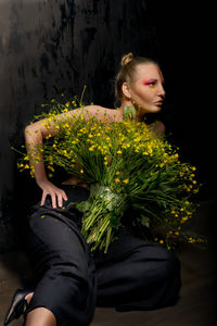 Girl looking down while sitting by plants