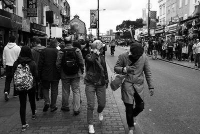 Rear view of people walking on city street