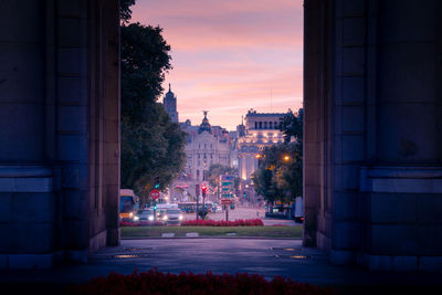 Through famous alcala gate view of cityscape with buildings against sunset sky in madrid