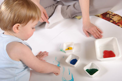 High angle view of girl with brother painting on paper