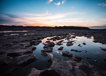 Tranquil view of wet landscape against sky during sunset