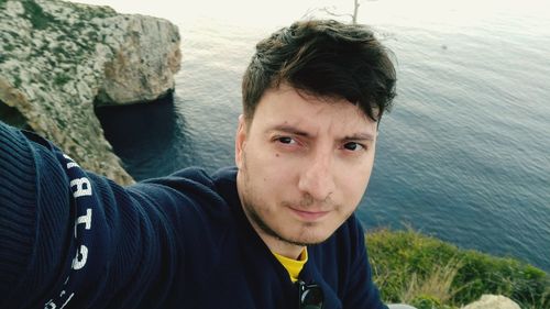 Portrait of young man standing against sea