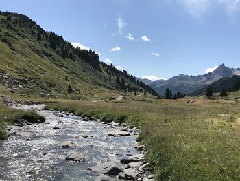 Scenic view of stream by mountains against sky