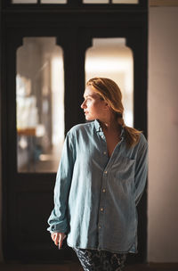 Woman looking away while standing against wall