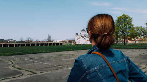 Woman looking at blue sky while standing by sport court