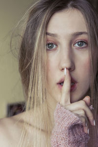 Blonde woman with green eyes showing shh sign