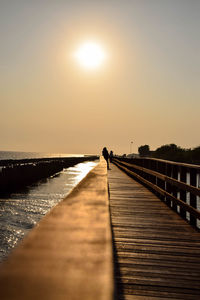 Pier over sea against clear sky during sunset