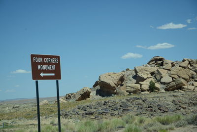 Road sign by mountain against sky