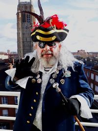 Portrait of senior man in costume standing against sky in city