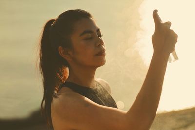 Side view of young woman standing against sky