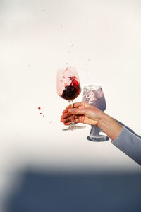 Hand holding glass of wine against white background