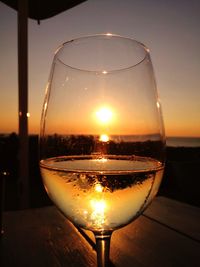 Close-up of wineglass on table against sky during sunset