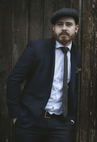 Portrait of young man standing against wall